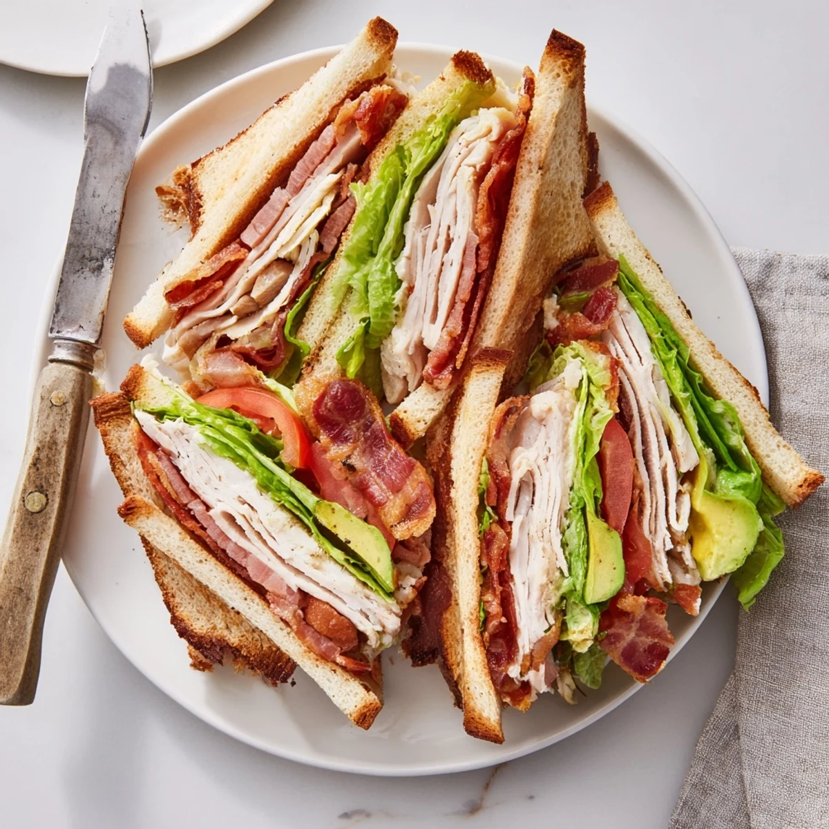 Triple-decker California Club Sandwich stacked with turkey, bacon, avocado, lettuce, and tomato on toasted bread