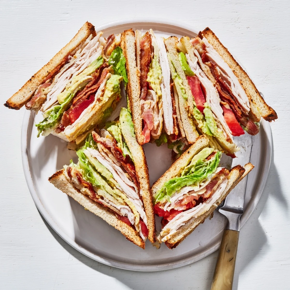 Golden toasted California Club Sandwich layers featuring roasted turkey, crispy bacon, creamy avocado and fresh vegetables
