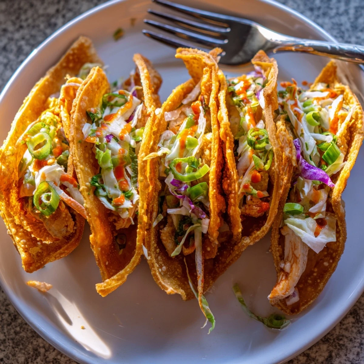 Golden crispy Asian chicken wonton tacos topped with colorful crunchy slaw and tangy sriracha mayo drizzle
