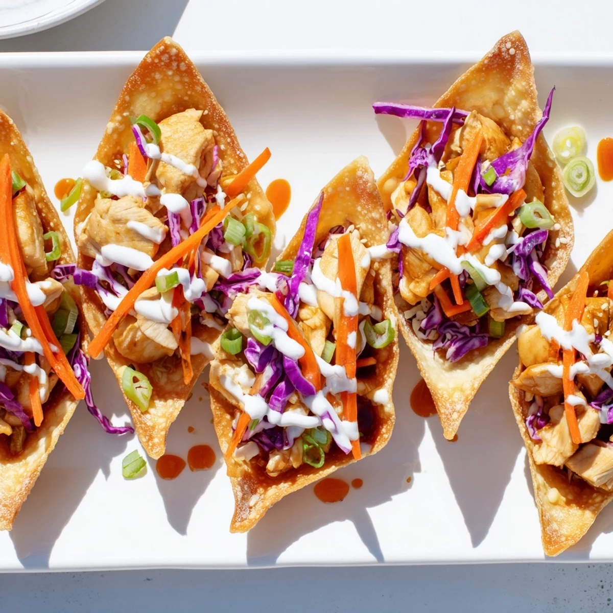 Golden chicken wonton tacos topped with colorful cabbage slaw and spicy sriracha drizzle