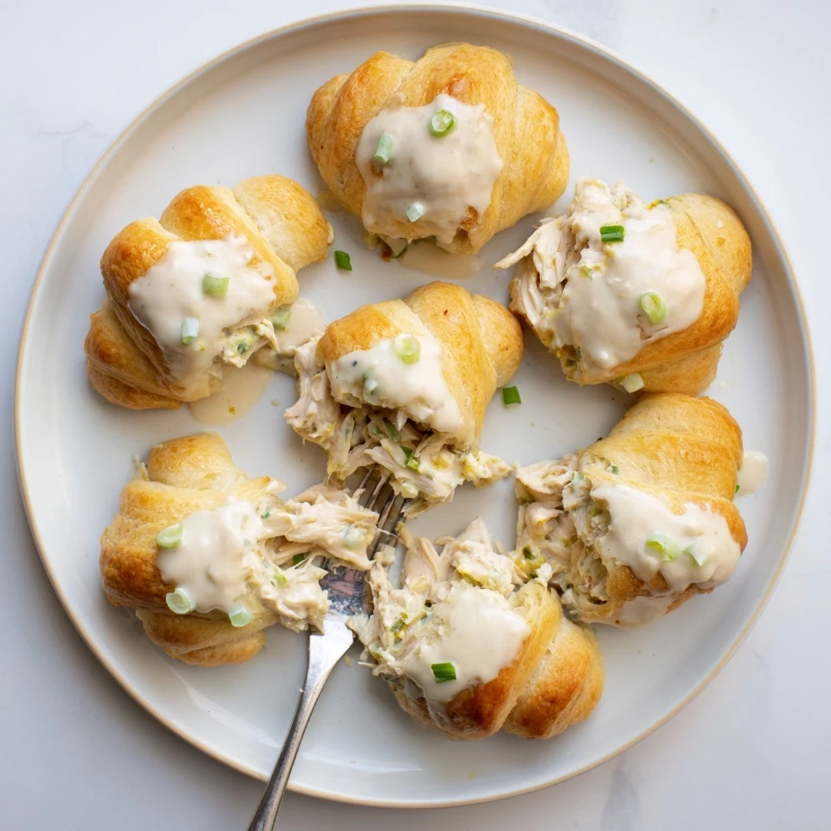 Flaky baked chicken pillows with tender shredded chicken center topped with homemade parmesan cream sauce