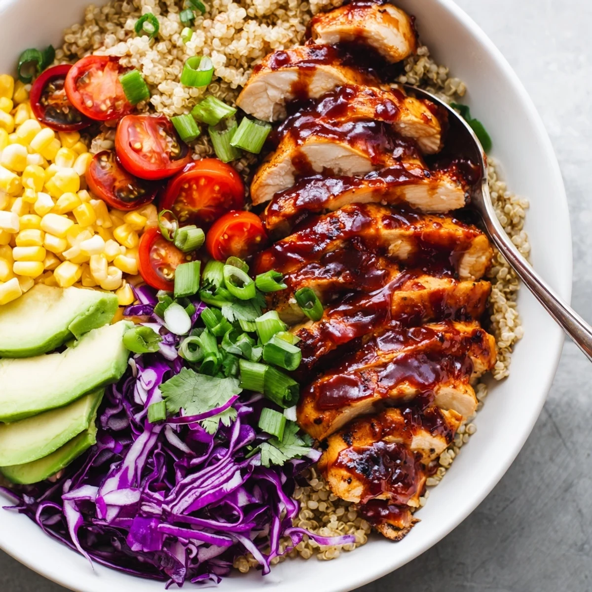 Grilled barbecue chicken grain bowl featuring vibrant cabbage, corn, and cilantro garnish