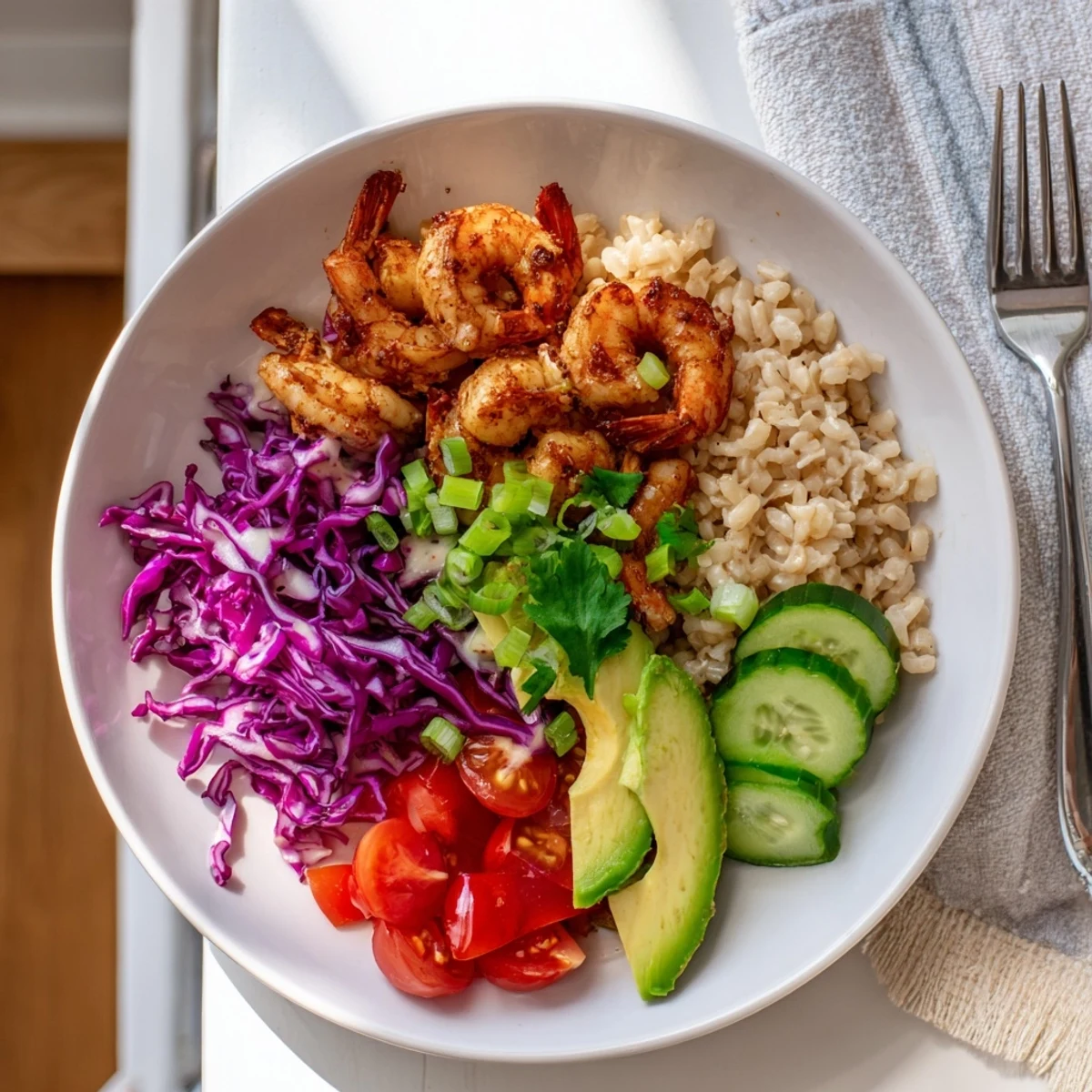 Golden smoked paprika shrimp grain bowl topped with avocado and fresh cilantro