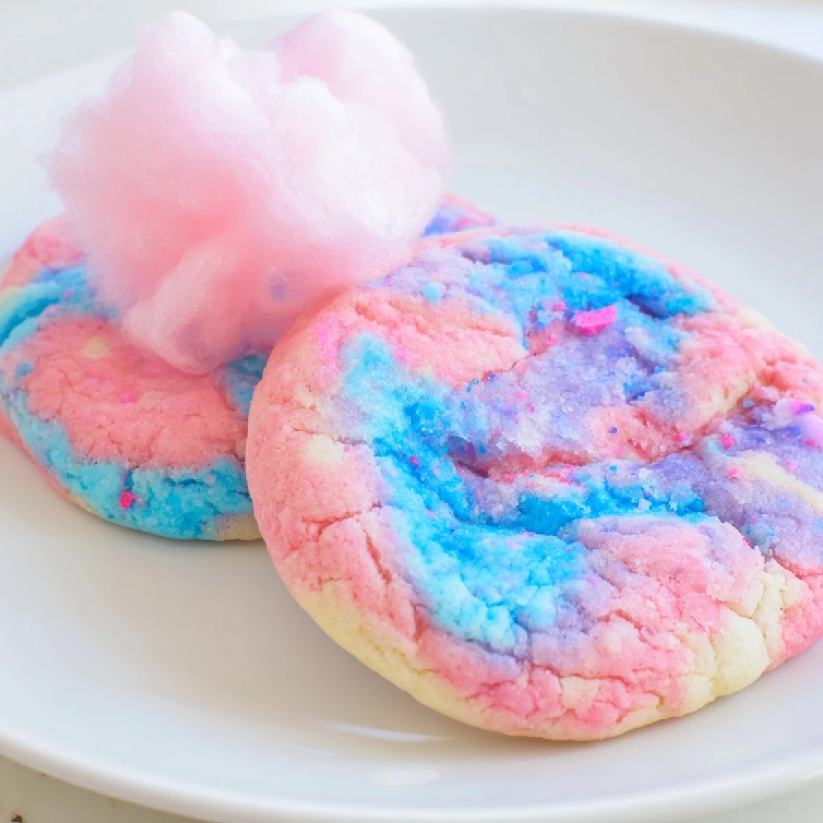 Swirled pink and blue cotton candy cookies with soft chewy centers on a parchment-lined baking sheet