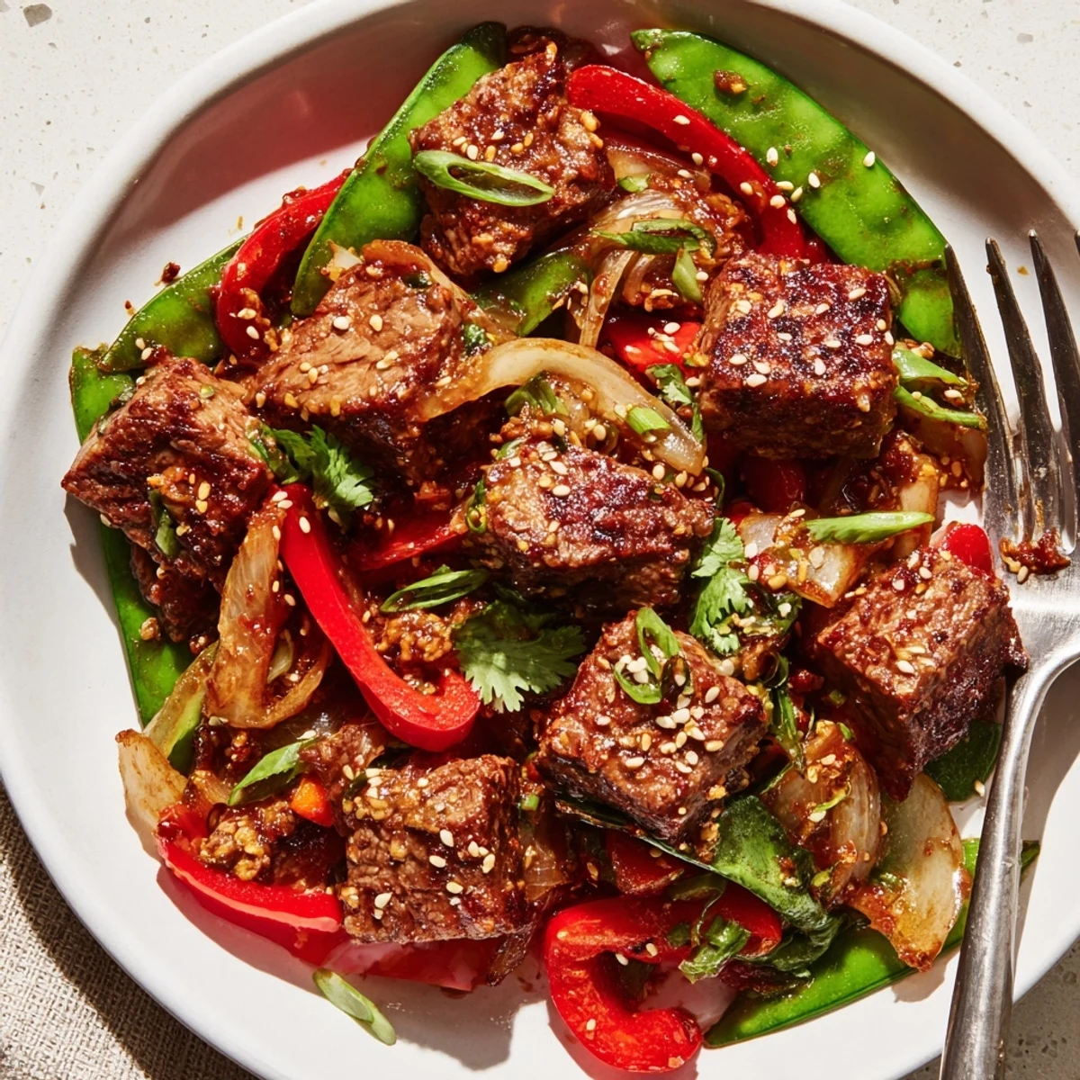 Tender Asian inspired cube steak seared golden alongside vibrant bell peppers and snap peas