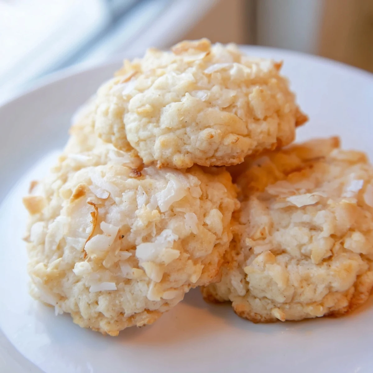 Golden soft and buttery coconut cookies with chewy shredded coconut edges on a rustic baking sheet