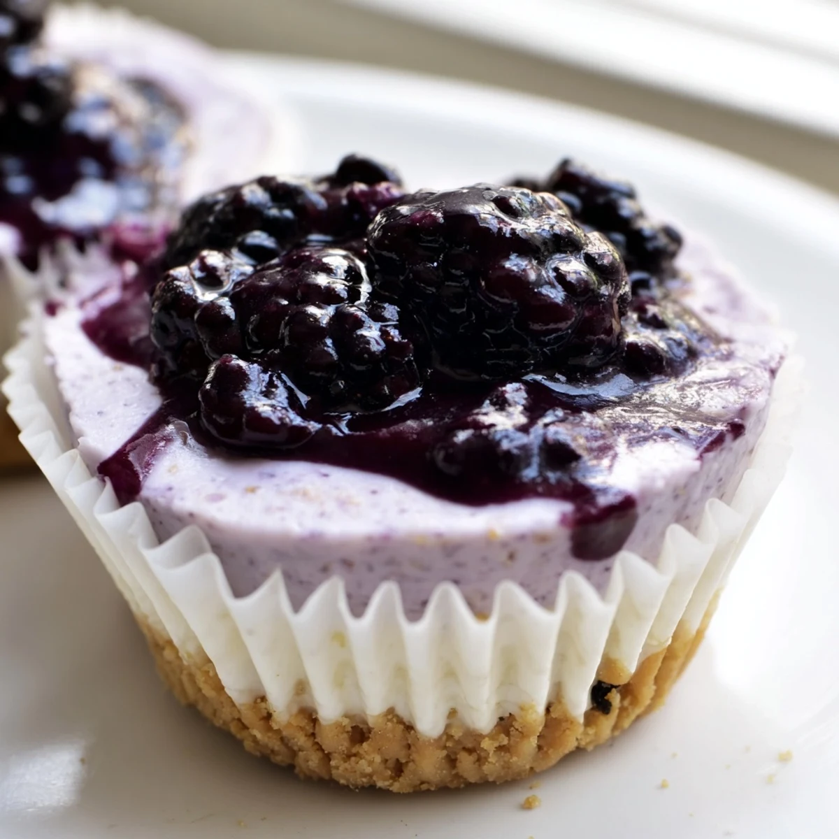Individual no bake mini blackberry lavender cheesecakes with whipped cream crowns and fresh berry garnish