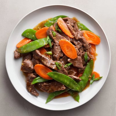 Tender beef, crisp carrots, and bright snow peas create a vibrant weeknight stir fry.