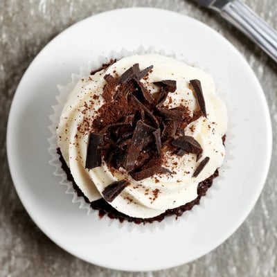 Rich chocolate cupcakes filled with coffee syrup and creamy mascarpone frosting on white plate