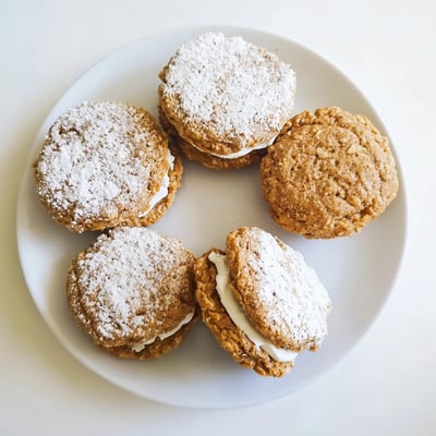 Close up of homemade oatmeal cream pies showing golden brown oatmeal cookies with white cream filling