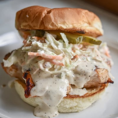 Heaping Alabama BBQ Chicken Chopped Sandwich with coleslaw and pickles on soft golden bun