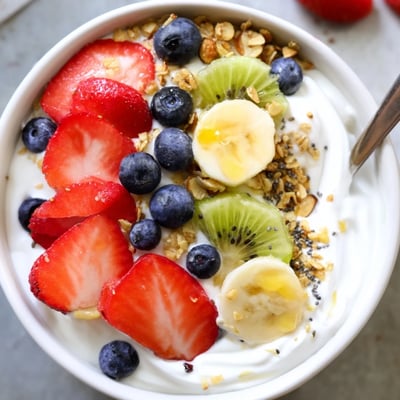Vibrant yogurt fruit bowl featuring sliced banana, kiwi, and a drizzle of honey